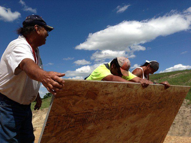 A group of people are working on a large piece of plywood at Pine Ridge Reservation