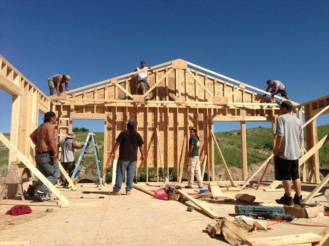 A group of men are working on a wooden structure at Pine Ridge Reservation