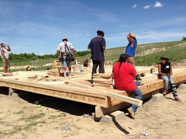A group of people are working on a wooden structure at Pine Ridge Reservation