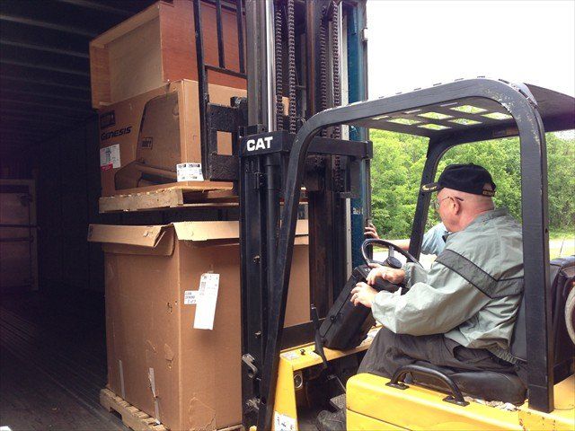 A man is driving a yellow cat forklift at Pine Ridge Reservation