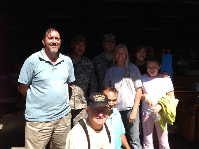 A group of people posing for a picture with one man wearing a veterans hat at Pine Ridge Reservation