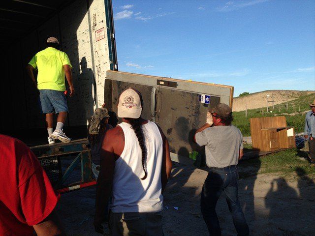 A group of men are loading a large piece of wood into a truck at Pine Ridge Reservation