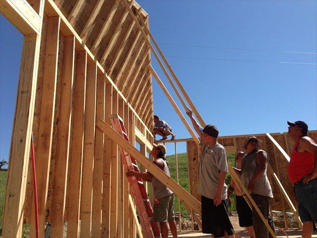 A group of people are working on a wooden structure at Pine Ridge Reservation