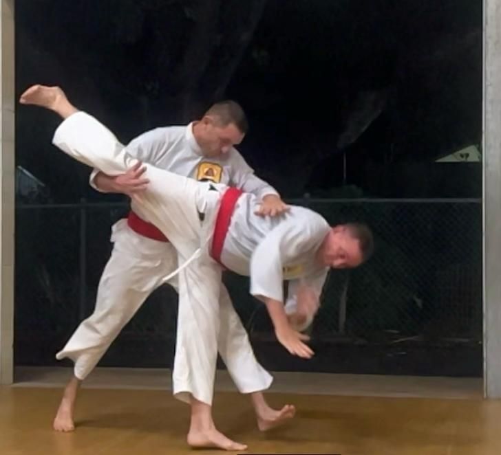 Two men are practicing martial arts with one wearing a shirt that says a on it