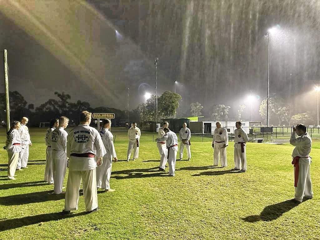 A group of people are standing in a field in the rain.