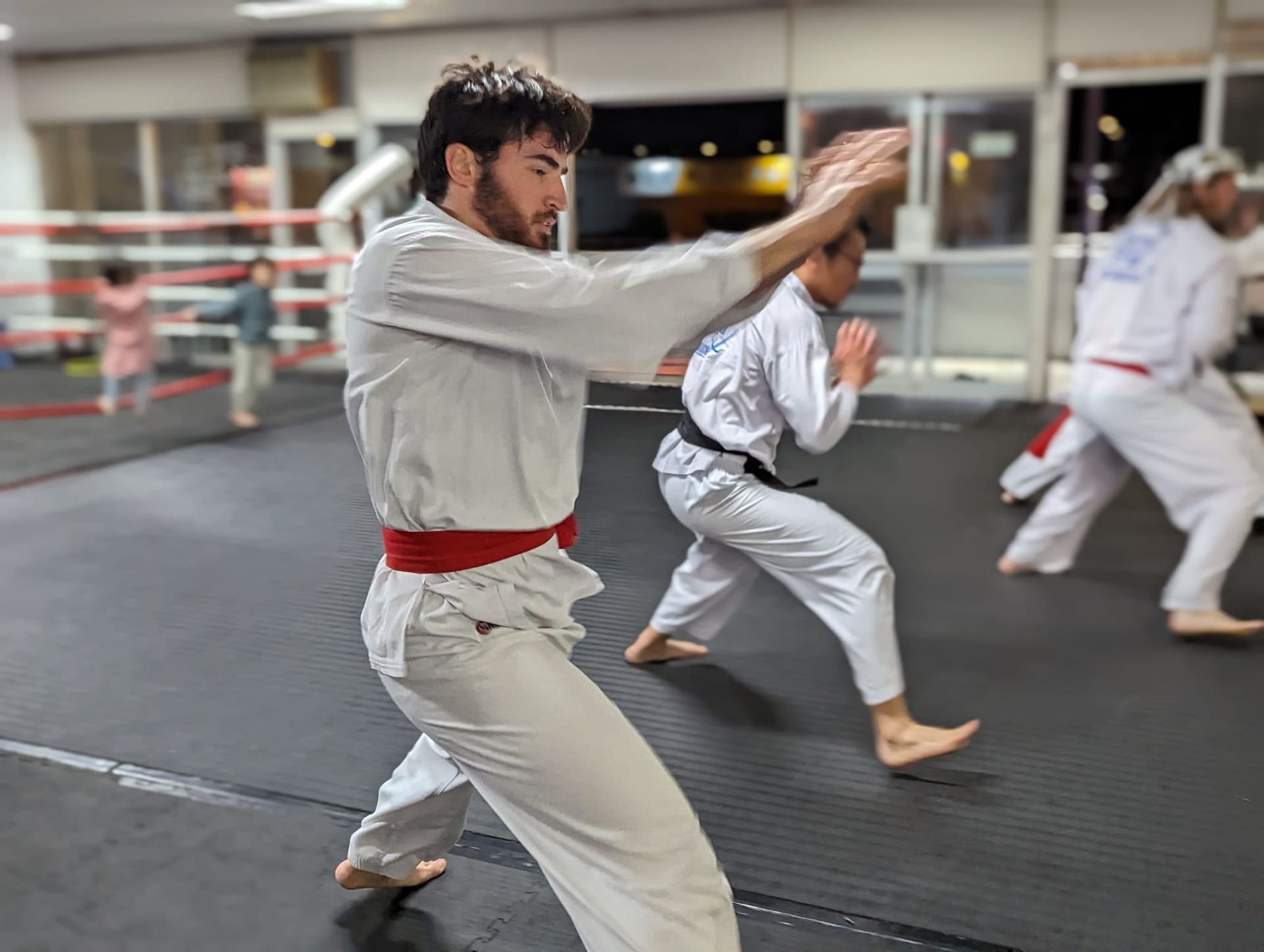 A group of people are practicing karate in a gym.