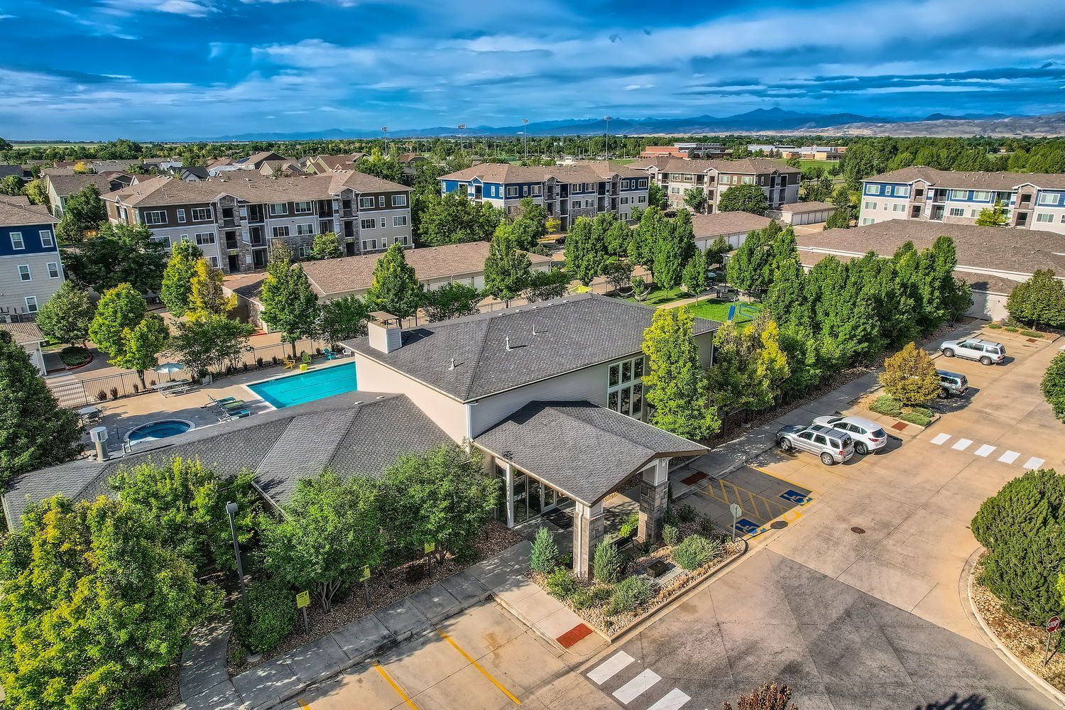 Aerial view of a modern apartment community with a central clubhouse, pool, and surrounding buildings.