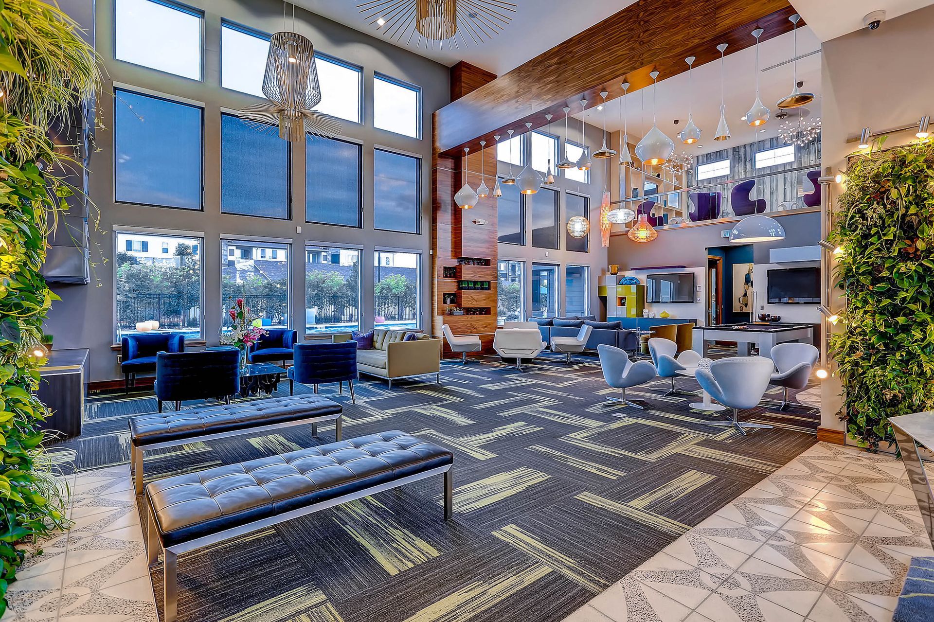 Spacious modern community lounge with floor-to-ceiling windows, couches, and pendant lights.