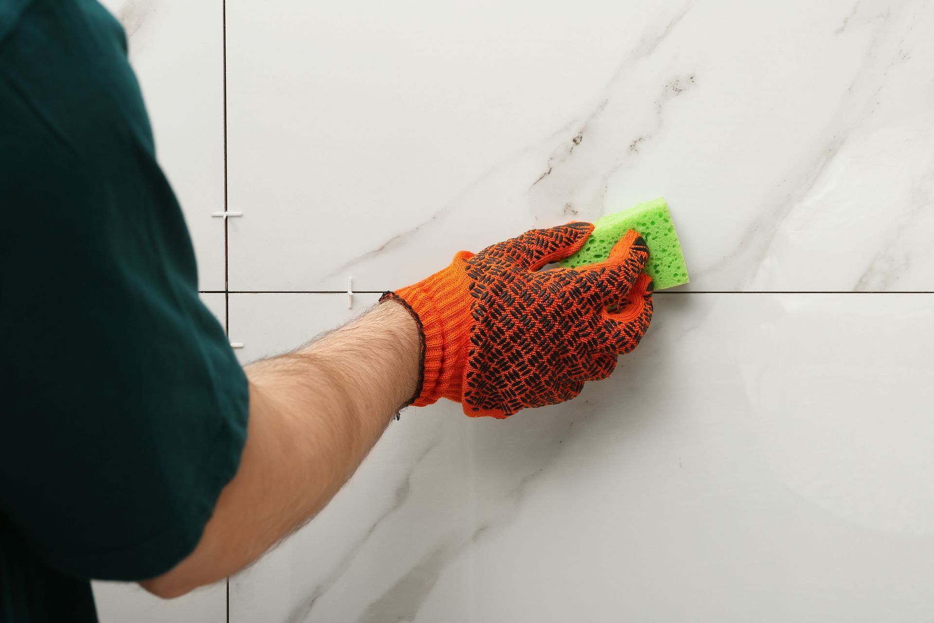 Person Uses a Green Sponge to Clean White Tile — Tampa, FL — A&A's Complete Services, Inc.