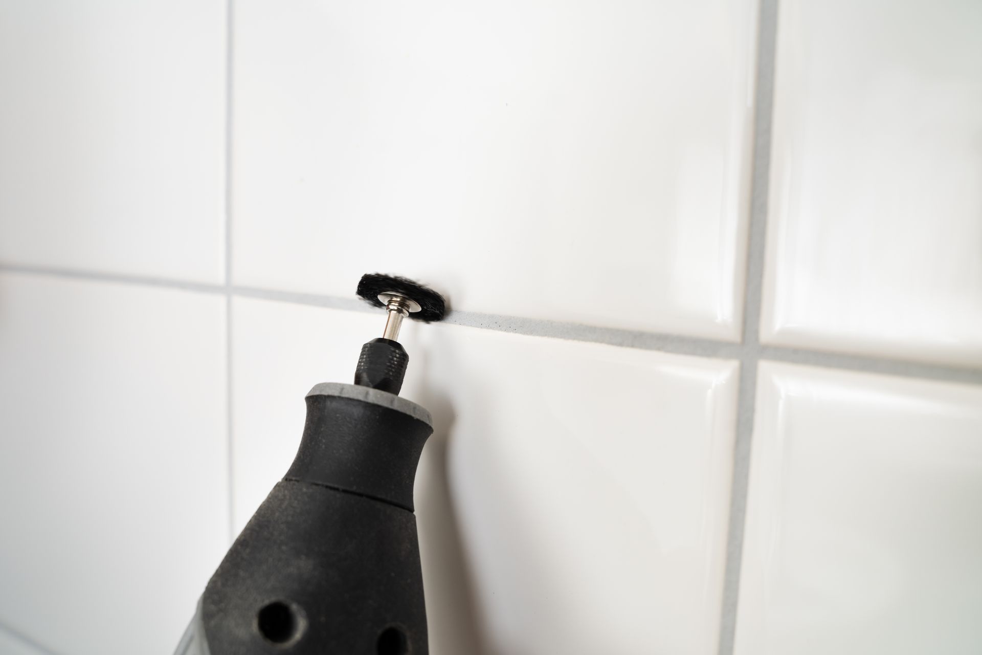 Dremel Tool Grinding Grout Between White Tiles — Tampa, FL — A&A's Complete Services, Inc.