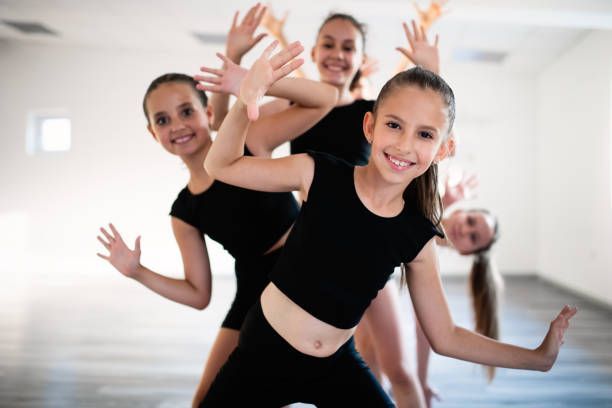 Dance Classes for Kids - Group of fit happy children exercising ballet in studio together