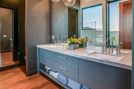 Modern bathroom vanity with double sinks, mirror, flowers, and warm wood flooring