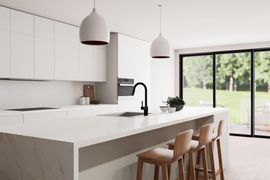 Modern white kitchen with island, wooden stools, pendant lights, and large sliding glass doors