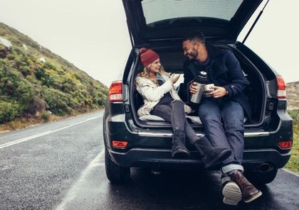 A man and a woman are sitting in the back of a car.