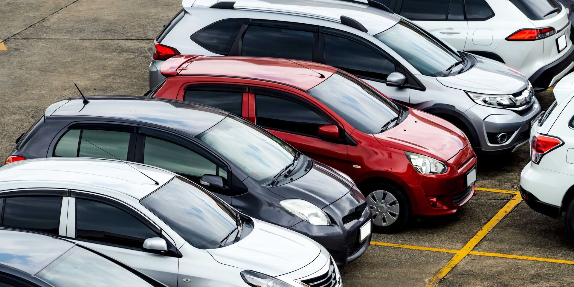 A row of cars are parked in a parking lot.