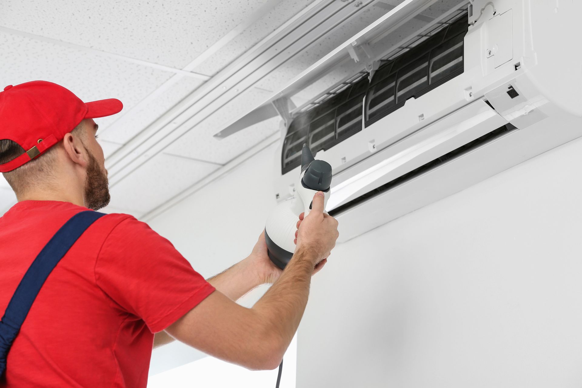 Technician cleaning office air conditioning unit