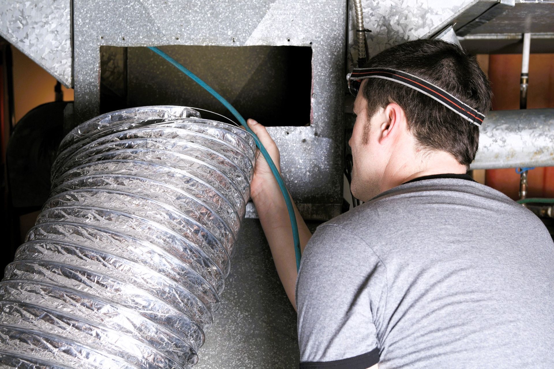Duct cleaning worker connecting flexible duct to ventilation system