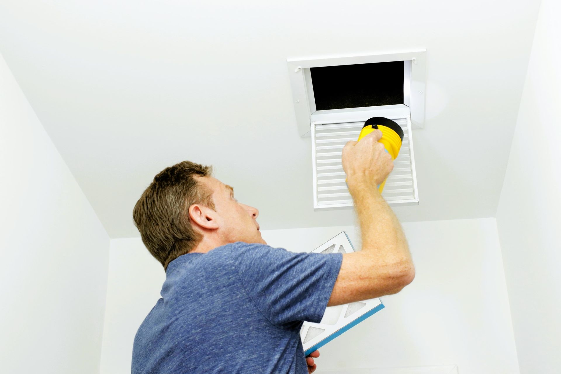 Person changing an air filter in a ceiling HVAC unit