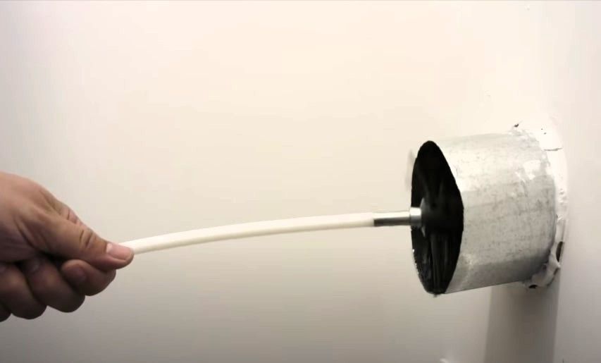 Hand cleaning dryer vent duct with brush tool to remove lint buildup