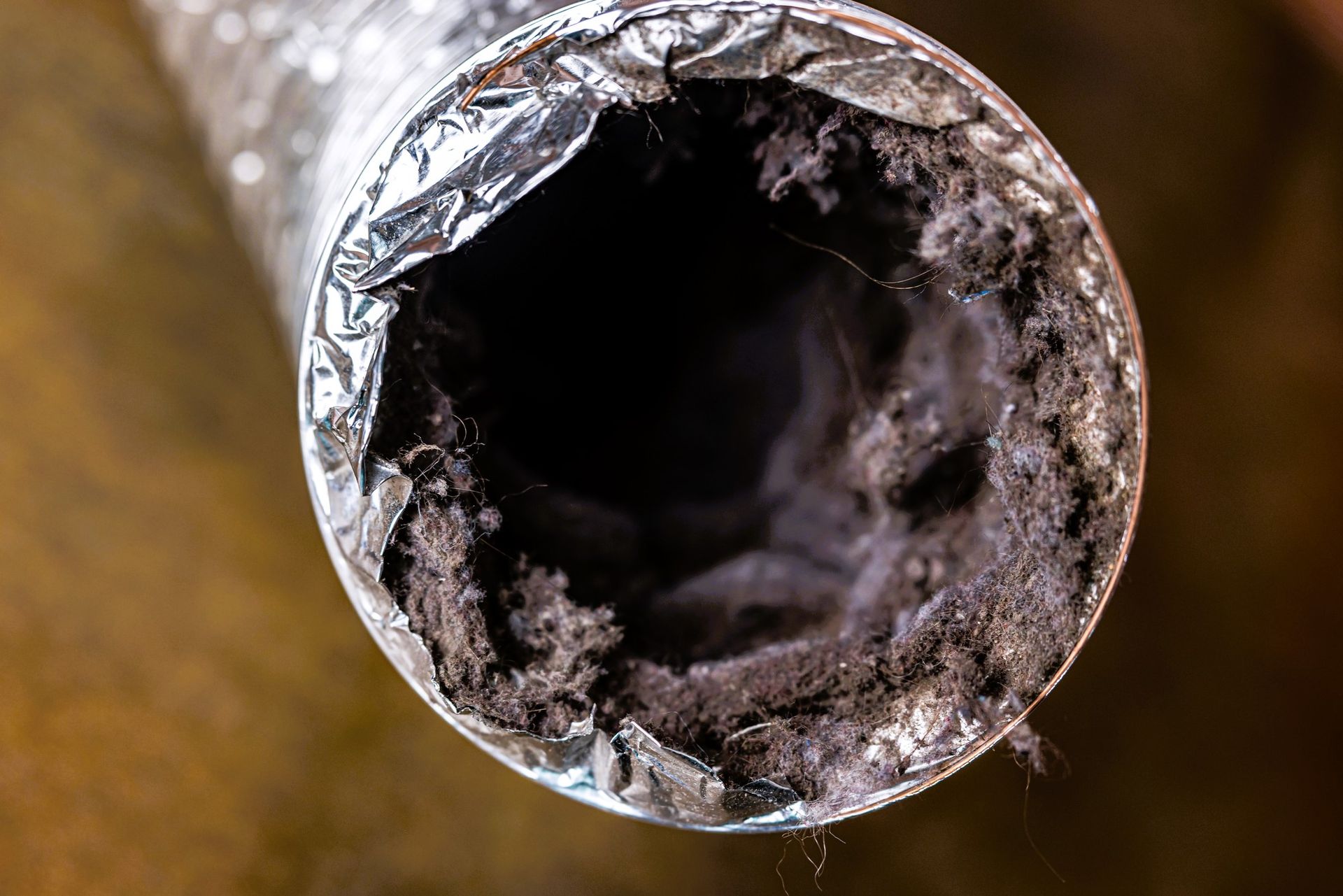 A flexible aluminum dryer vent duct clogged with lint, dust, and dirt