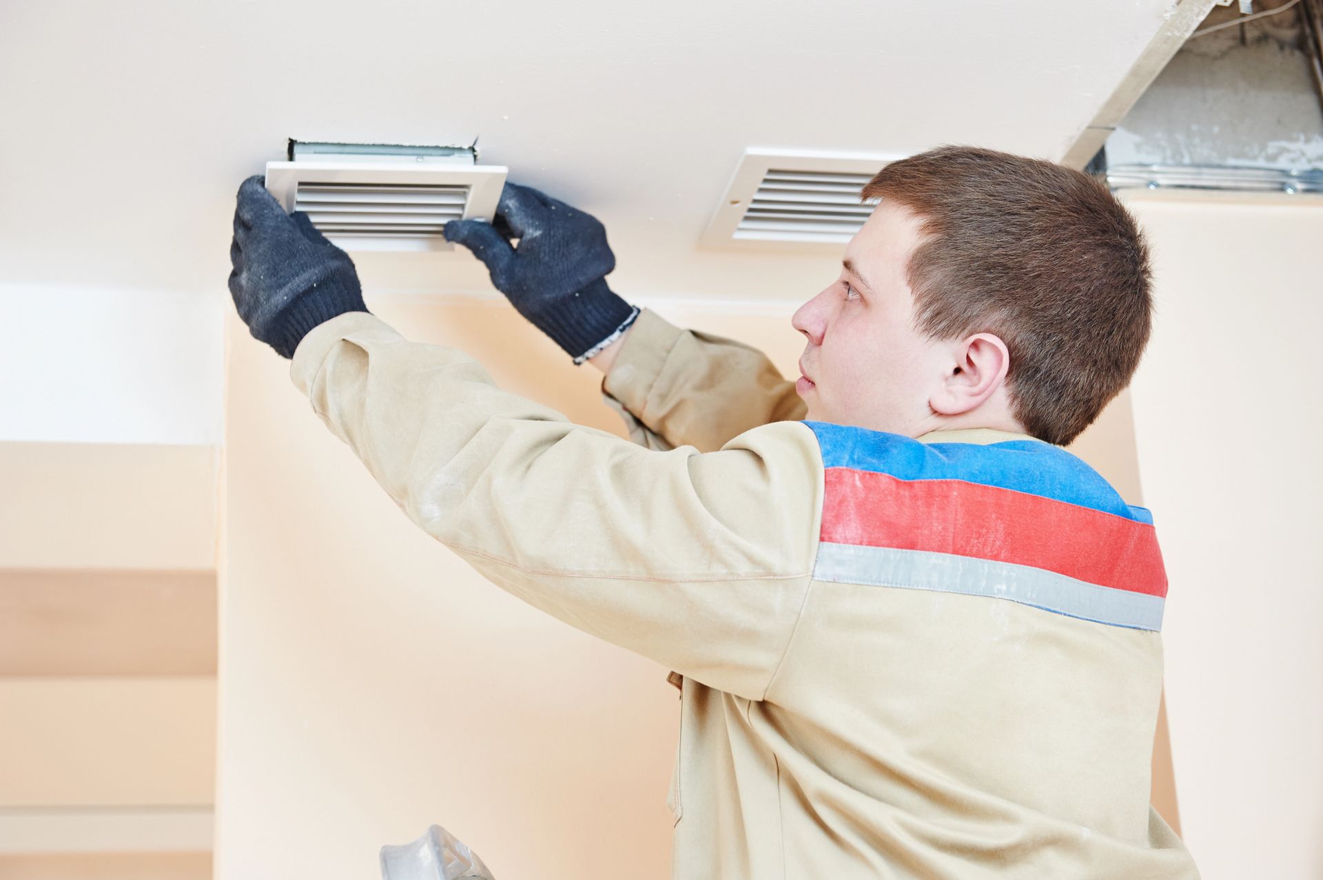 Technician repairing ceiling air vent for better HVAC efficiency