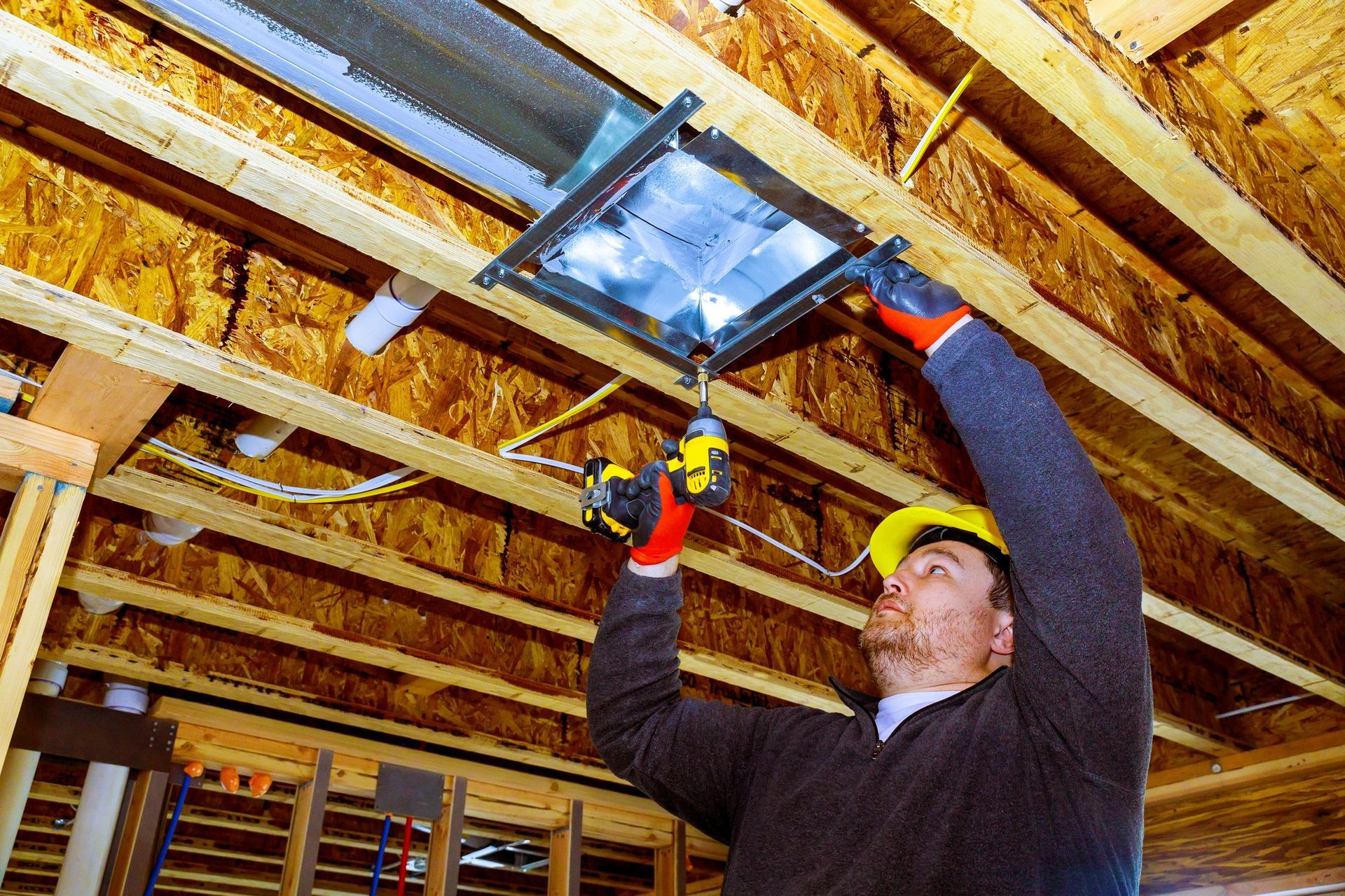 Professional installing new ductwork in home ceiling