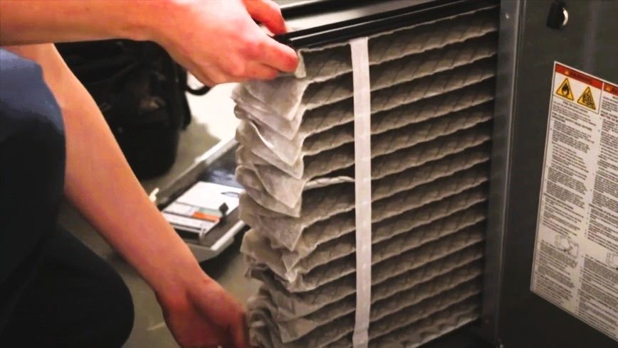 Person replacing a dirty air filter in an HVAC system.