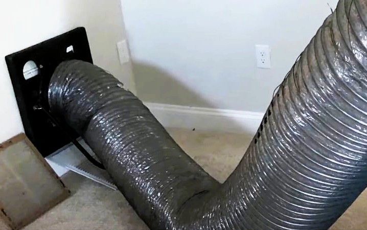 Flexible air duct extending from a floor vent across a carpeted room.