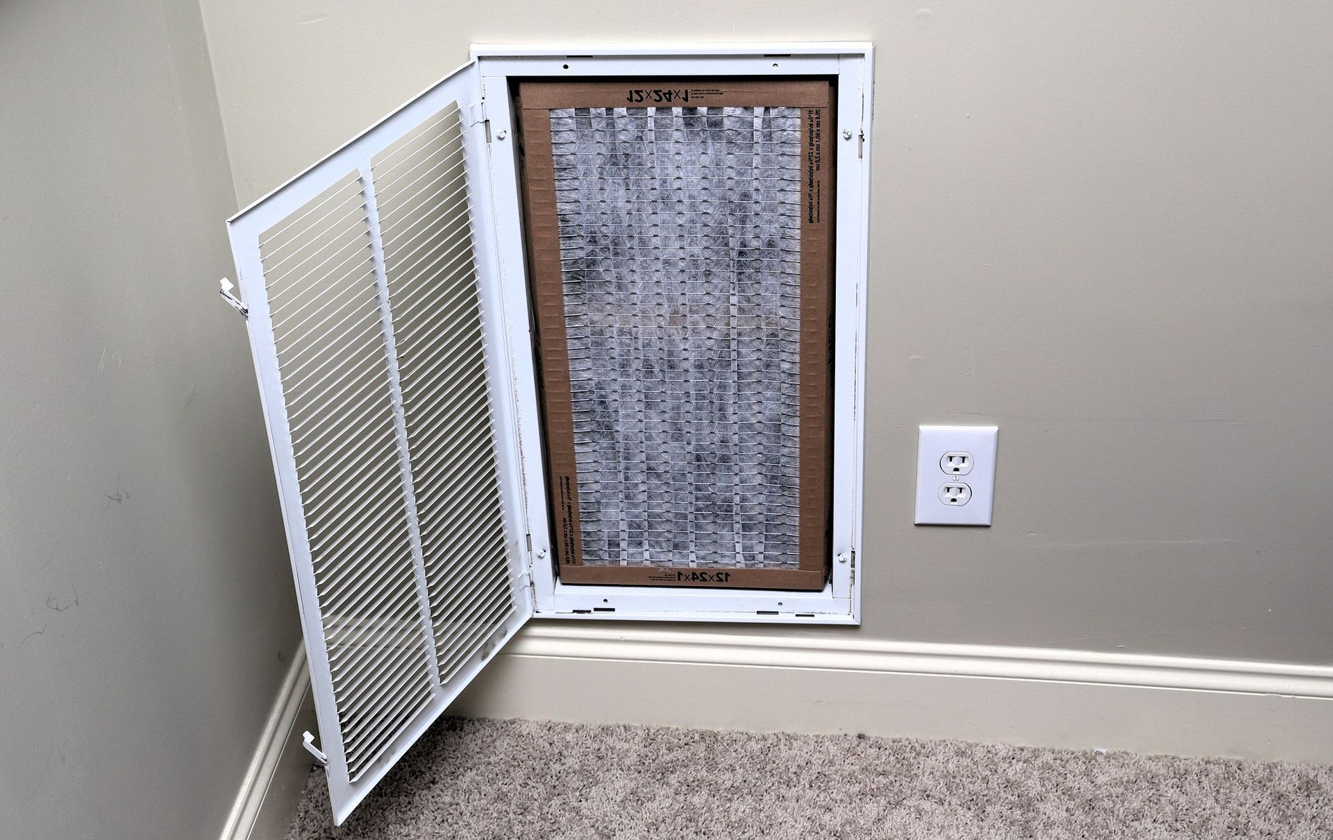 white vent cover with gray air filter on beige wall