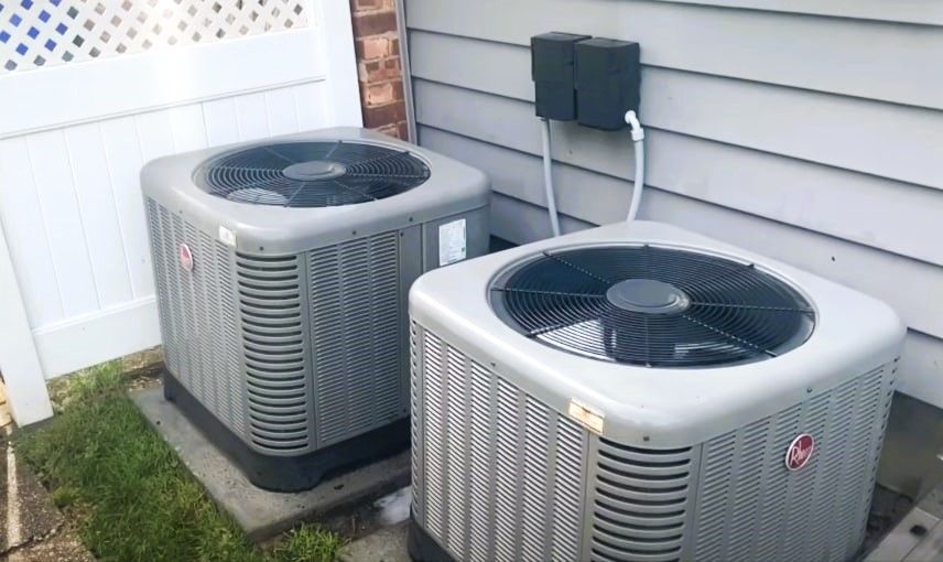 Two air conditioning units beside a house with a white lattice fence.