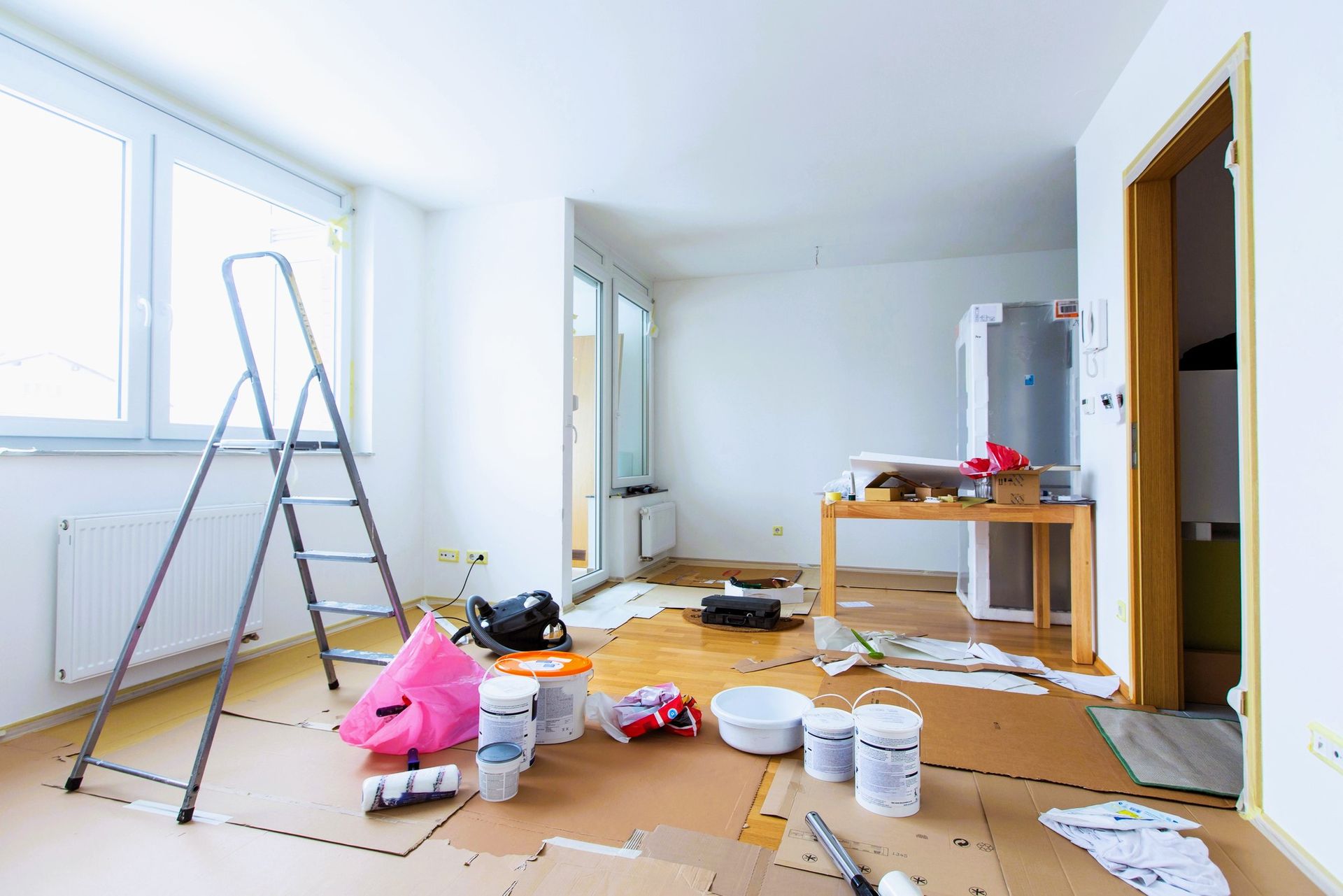 Room with paint supplies and ladder, showing disarray from home renovation