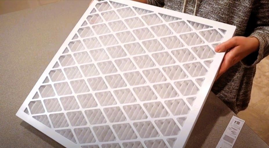 Person holding a rectangular reusable air filter on a countertop