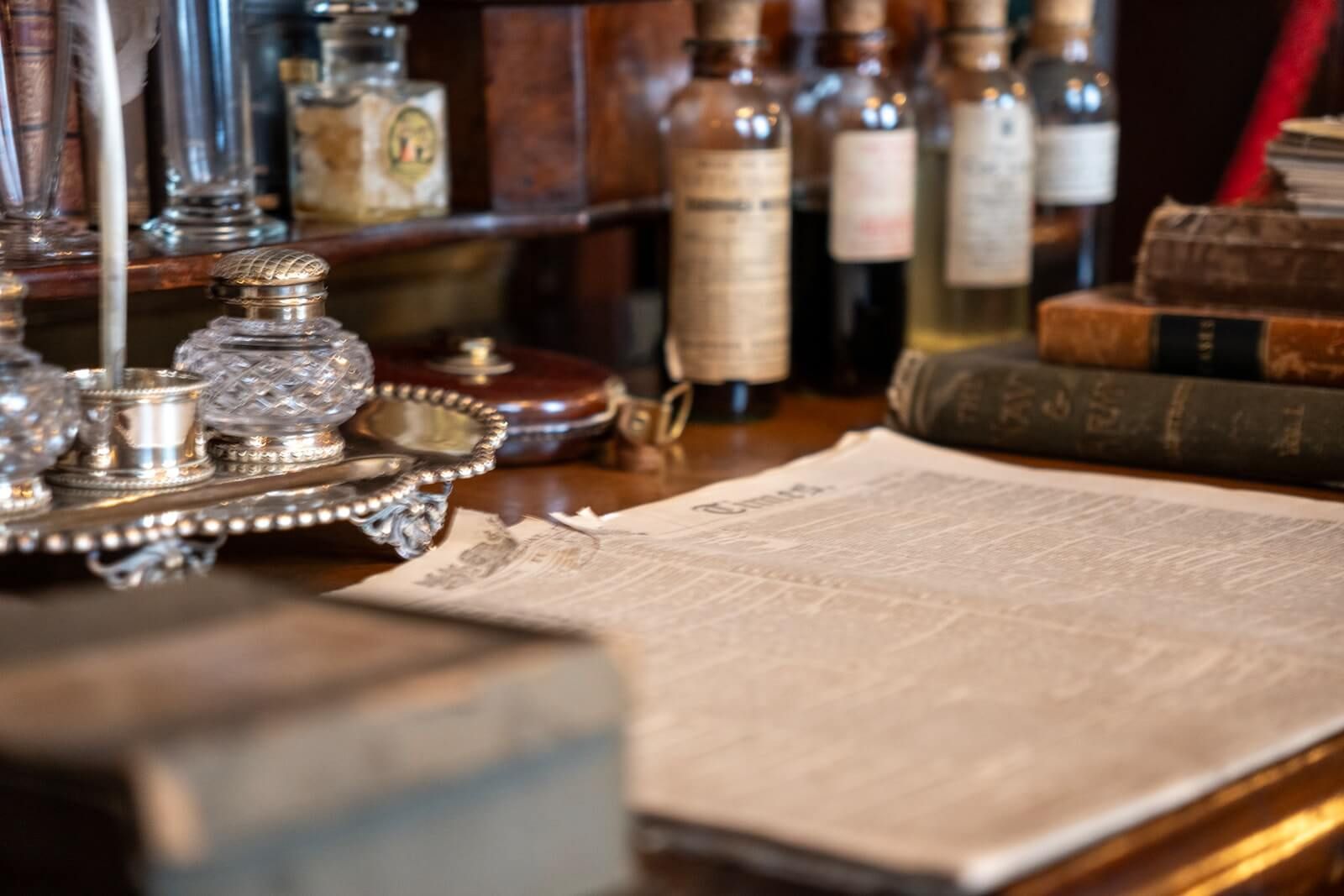 Desk with books, bottles, inkwells, and a document.