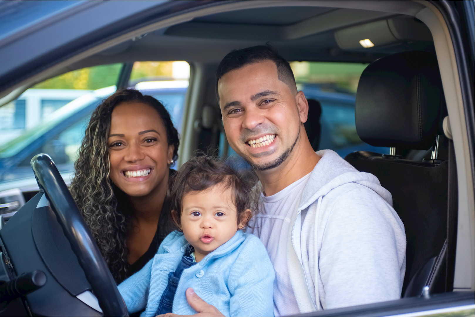 Man, woman, and child sitting in car in front, smiling | Eagle Transmission & Auto Repair