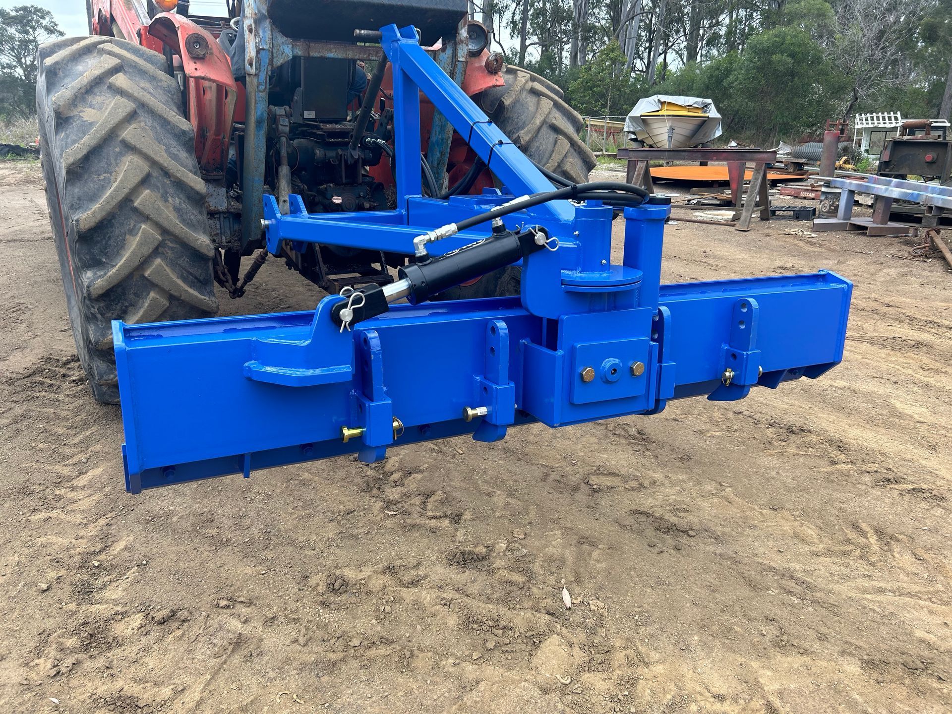 A blue tractor is parked in a dirt field.— Wingham Farm Machinery in Wingham, NSW