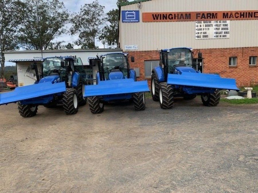 Three Blue Tractors Are Parked in Front of a Building That Says Wingham Farm Machine — Wingham Farm Machinery in Wingham, NSW