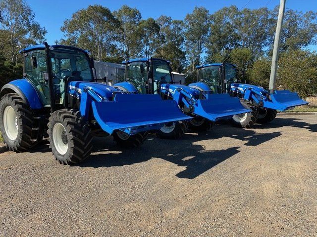 A row of blue tractors are parked in a gravel lot— Wingham Farm Machinery in Wingham, NSW