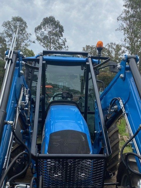 A Blue Tractor With a Basket on the Front  — Wingham Farm Machinery In Wingham, NSW