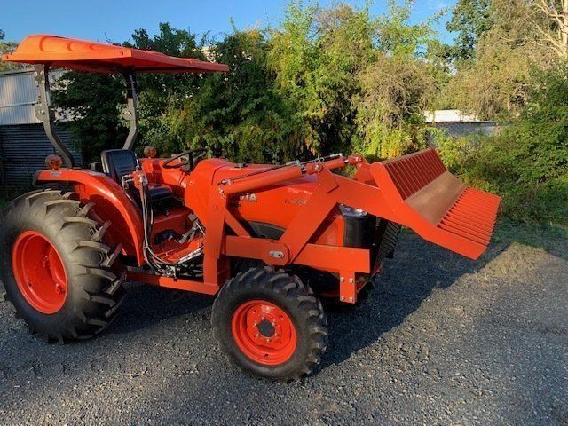 An Orange Tractor With a Bucket Attached to It is Parked on a Gravel — Wingham Farm Machinery in Wingham, NSW