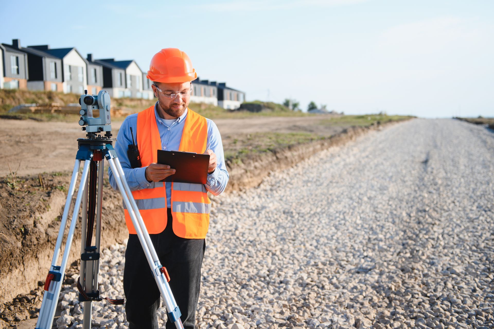 A surveyor is working at a residential construction.