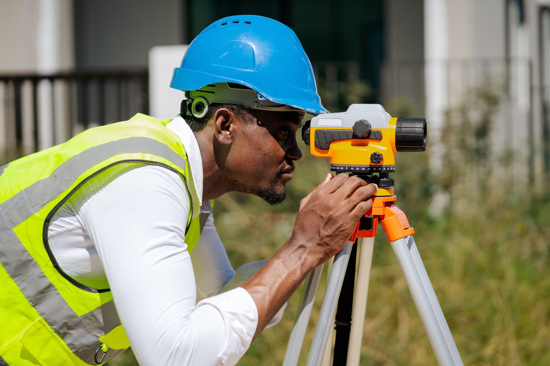 Male engineer in safety vest uses surveying instrument to measure levels at a construction site. Male engineer in safety vest uses surveying instrument to measure levels at a construction site.