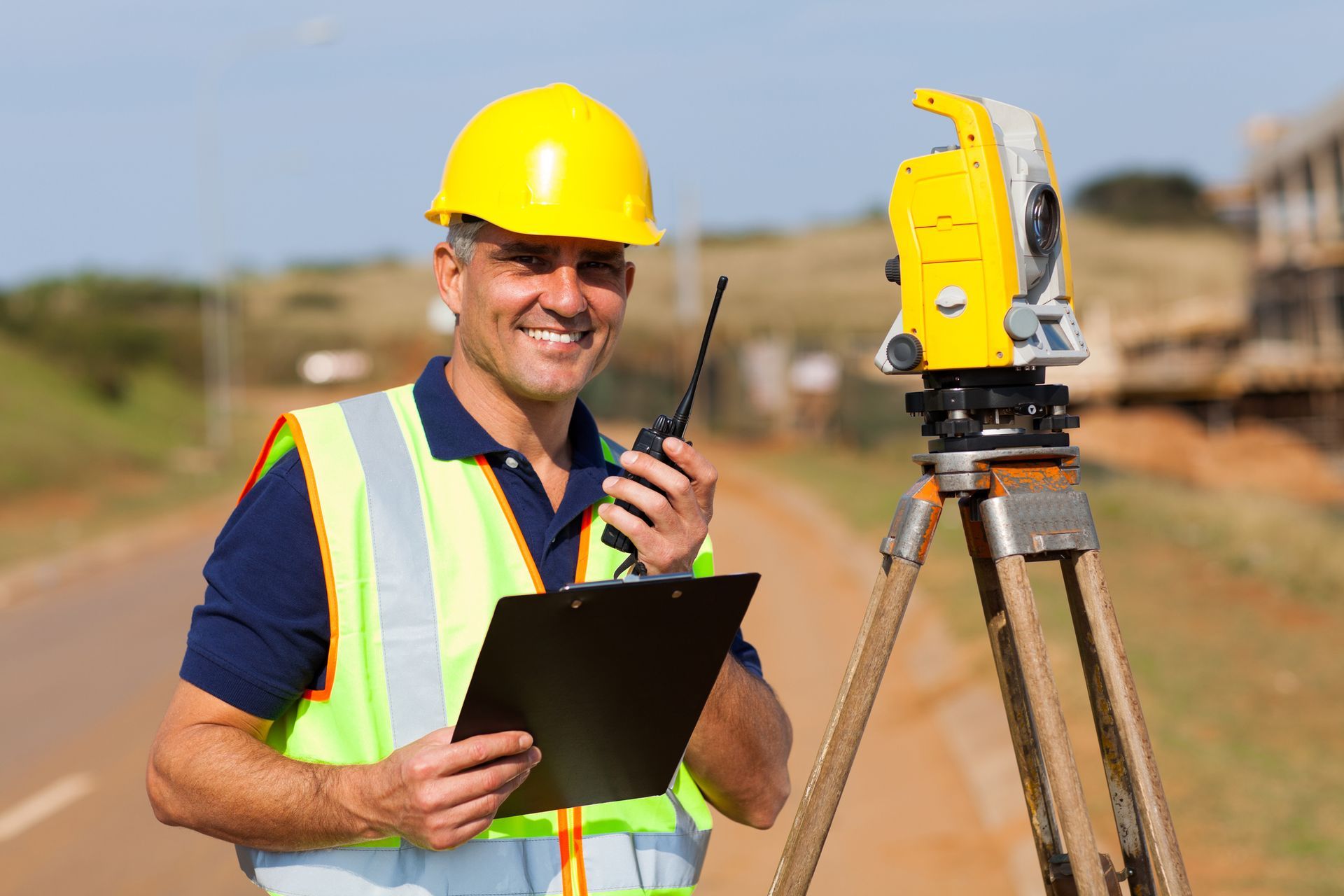 A person in a hard hat holding a clipboard and a radio