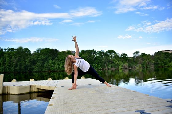 Yoga instructor in Side Angle pose on dock overlooking water