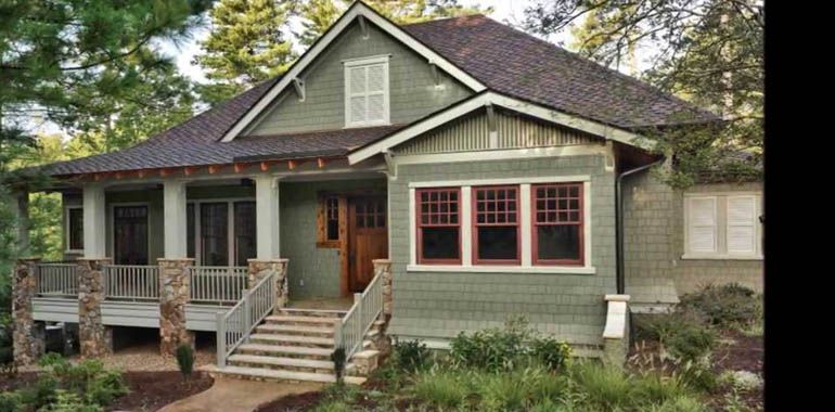 A green house with a porch and stairs