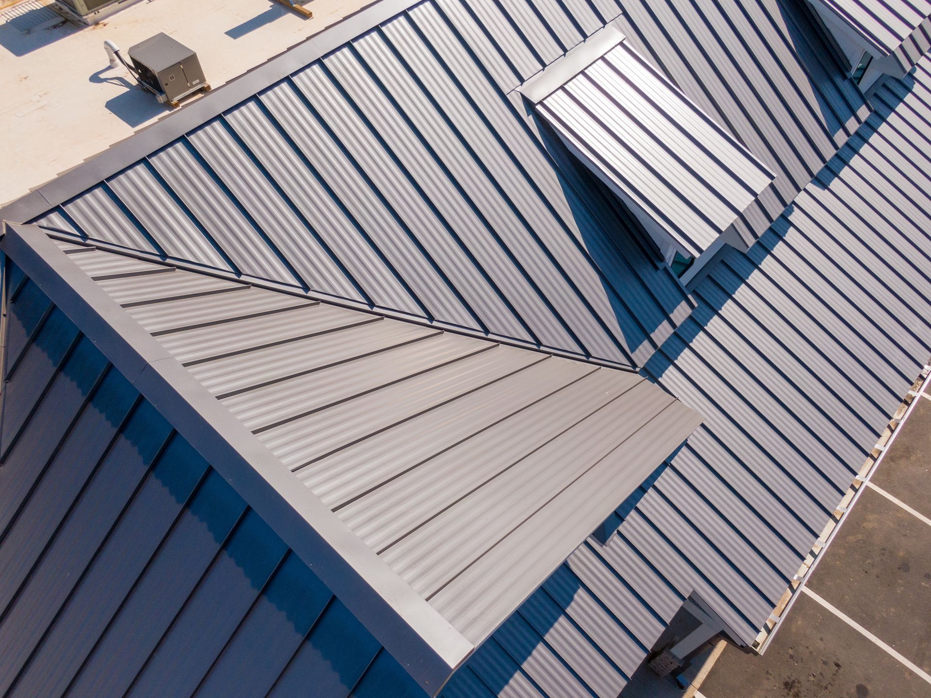 Aerial view of blue-gray metal roofs with vents and skylights on a building