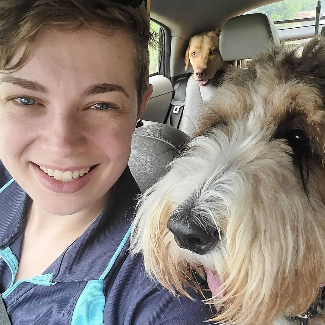 A woman is taking a selfie with two dogs in a car