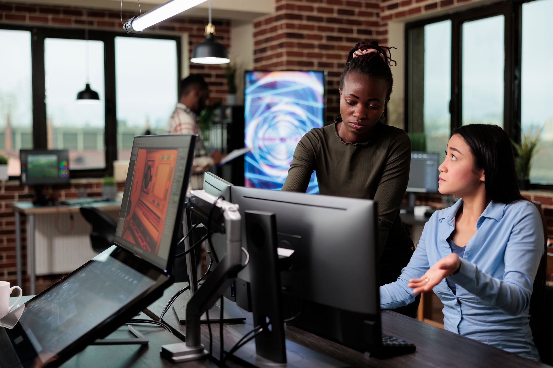 two women are looking at a computer screen in an office  | Apple Security Solutions