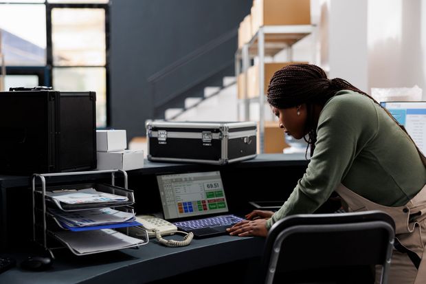 a woman is standing at a desk in front of a laptop computer  | Apple Security Solutions