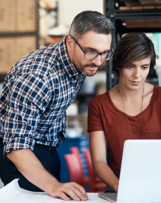 a man and a woman are looking at a laptop computer | Apple Security Solutions