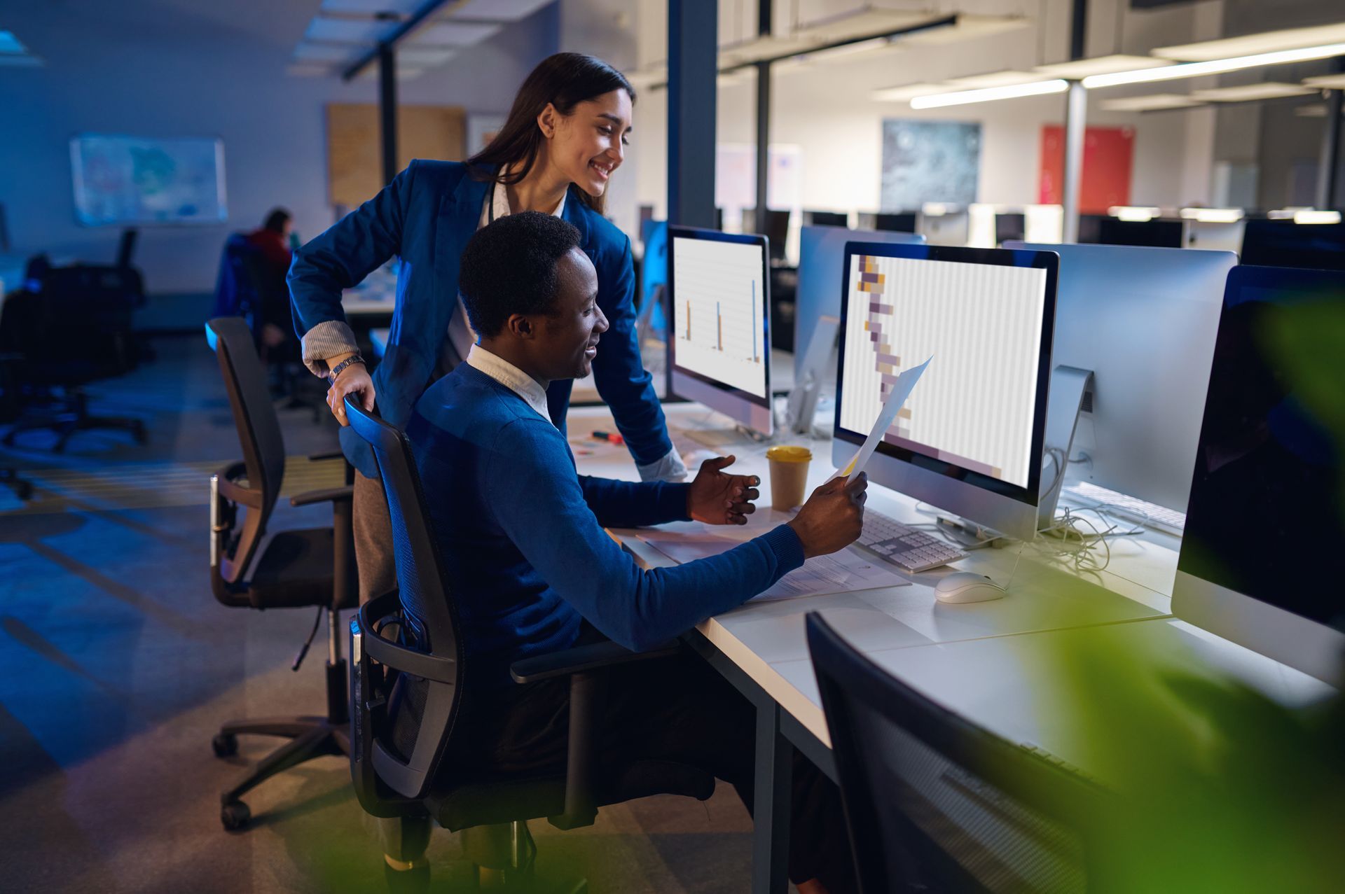 a man and a woman are looking at a computer screen in an office | Apple Business Security